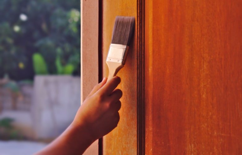 Een houten deur een nieuwe laag lak geven met een verfborstel