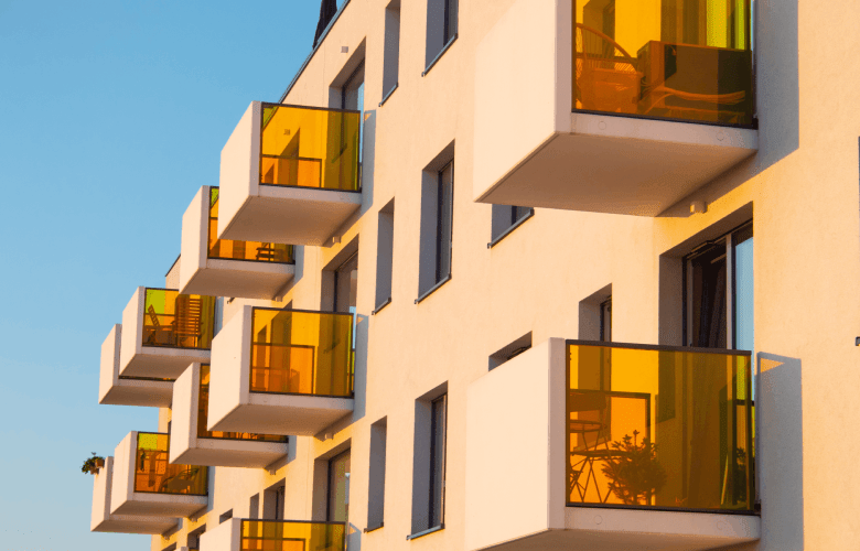 Een appartementsgebouw met zonnige balkons en geel getint glas.